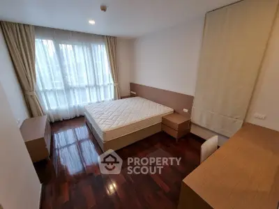 Spacious bedroom with hardwood floors and large window in modern apartment