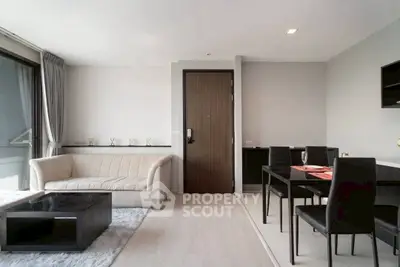 Modern living room with sleek furniture and dining area, featuring a cozy sofa and elegant decor.
