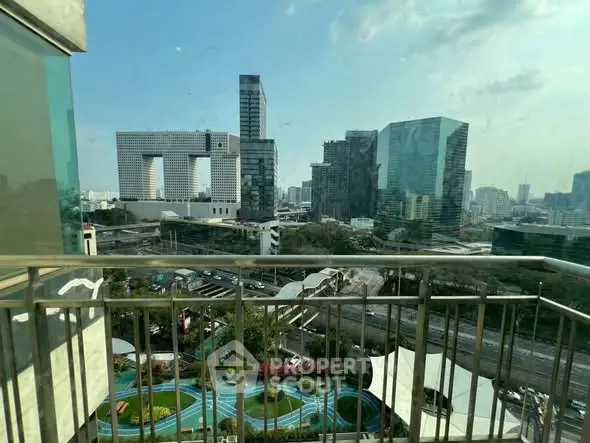 Stunning cityscape view from a high-rise balcony overlooking modern architecture and lush greenery.