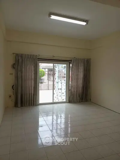 Spacious empty room with large window and tiled floor, ideal for customization.