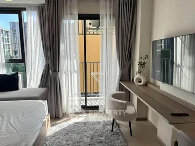 Modern bedroom with balcony view, stylish decor, and natural light in urban apartment.