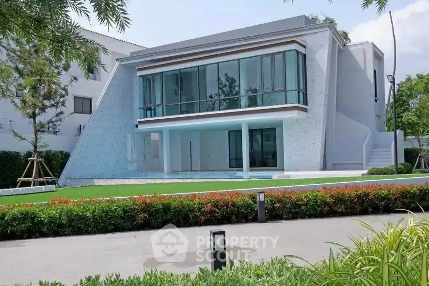 Modern architectural home with large glass windows and lush green lawn