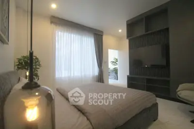 Modern bedroom with elegant lighting and large window, featuring a cozy bed and stylish built-in shelving.