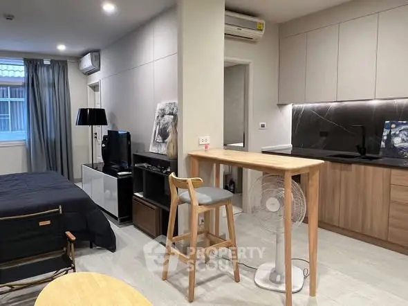 Modern studio apartment with sleek kitchen and cozy living area, perfect for urban living.
