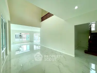 Spacious modern living room with glossy marble flooring and high ceilings, perfect for luxury living.