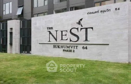 Modern condominium entrance at The Nest Sukhumvit 64 Phase 2 with lush green lawn.