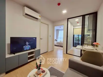 Modern living room with TV, air conditioning, and view into bedroom, featuring stylish decor.
