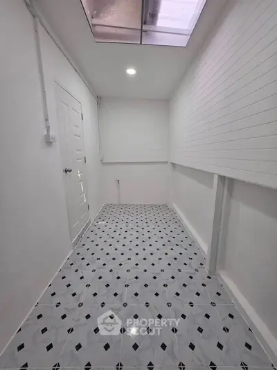 Bright and spacious utility room with modern tiled flooring and skylight, perfect for storage or laundry area.