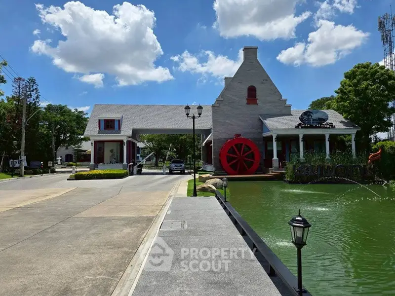 Charming property with unique architecture and scenic pond view under a bright blue sky.