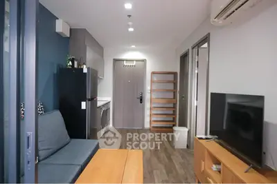 Modern living room with sleek furniture and integrated kitchen appliances in a cozy apartment.