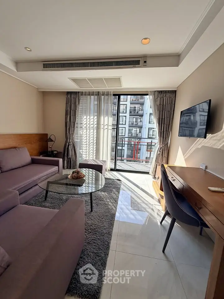 Modern living room with balcony view, featuring sleek furniture and abundant natural light.