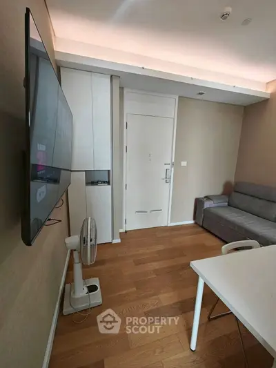 Modern living room with sleek TV, cozy sofa, and stylish wooden flooring.
