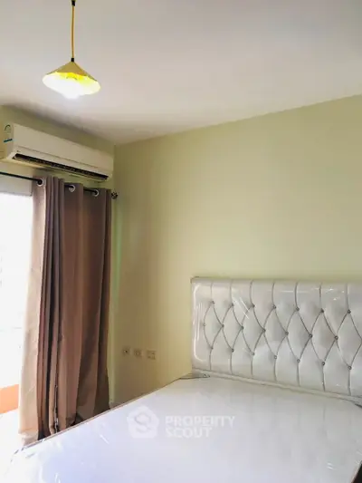 Modern bedroom with elegant tufted headboard and air conditioning, perfect for comfort and relaxation.