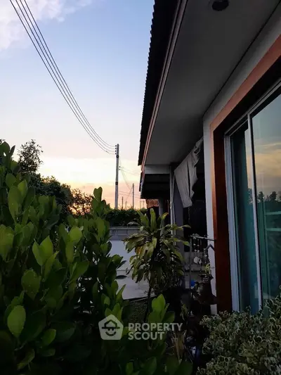 Charming suburban home exterior with lush greenery and sunset view.