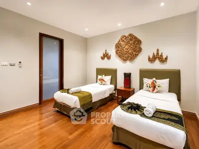Elegant twin bedroom with wooden flooring and decorative wall art in a modern home.