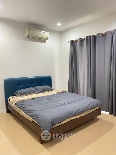Cozy bedroom with modern decor and air conditioning, featuring a comfortable bed and stylish curtains.