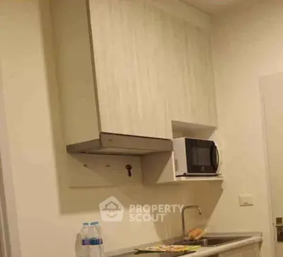 Compact kitchen with microwave and sink, ideal for modern living spaces.