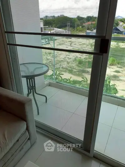 Charming balcony view from modern apartment with glass railing and cozy seating area.