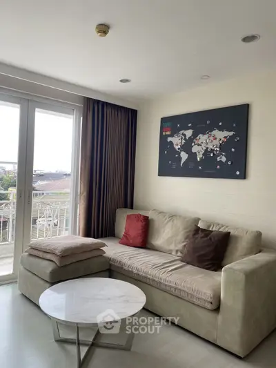 Modern living room with cozy sofa and world map decor, featuring large windows and natural light.