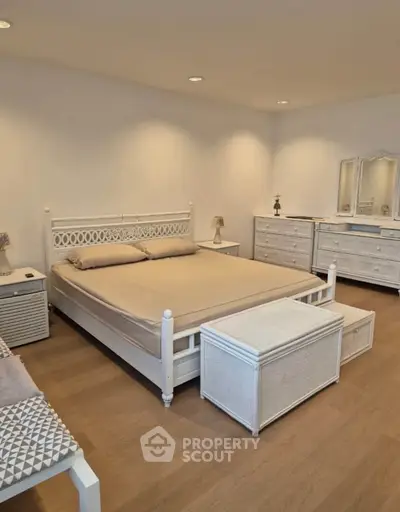 Spacious bedroom with elegant white furniture and cozy lighting, perfect for relaxation and comfort.