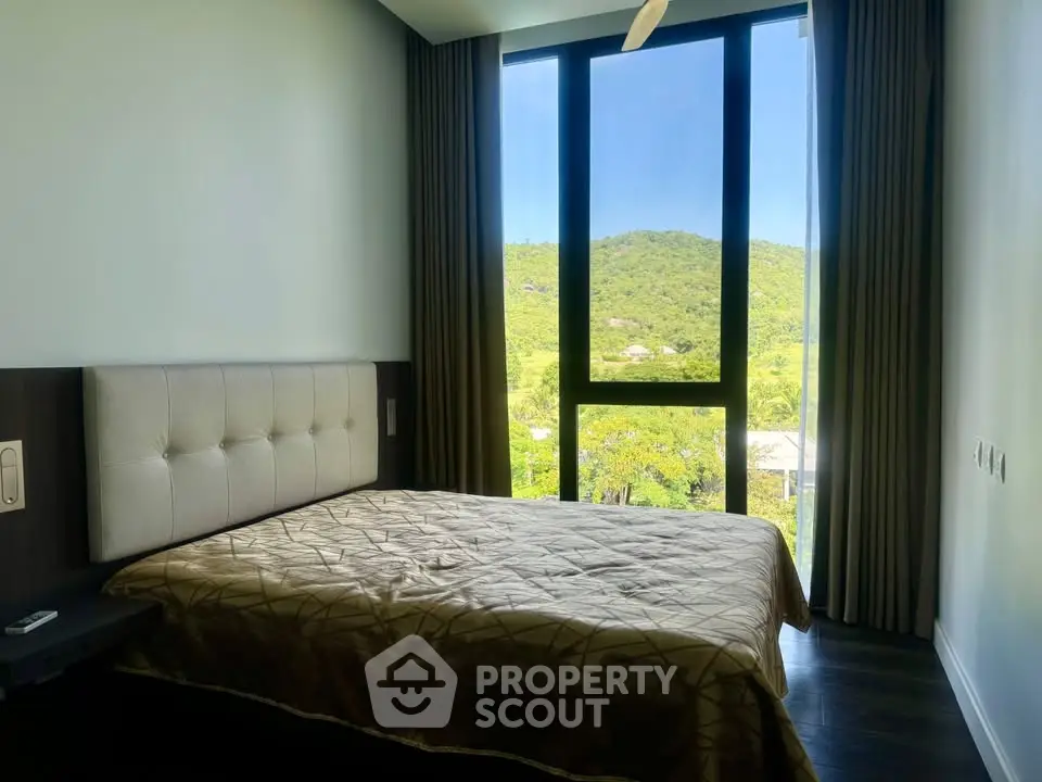 Spacious bedroom with large window offering stunning mountain views.