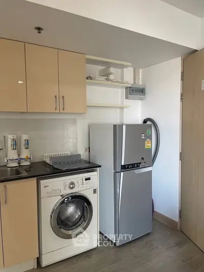 Compact kitchen with washing machine and fridge in modern apartment