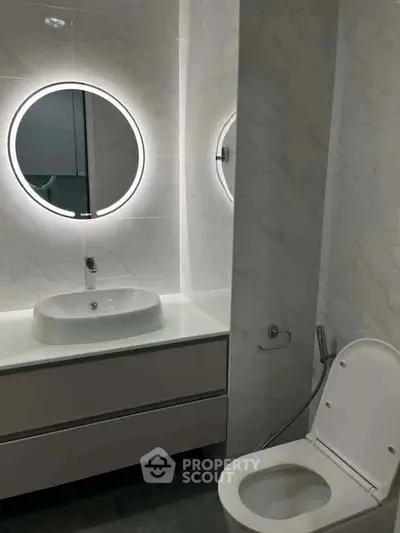 Modern bathroom with illuminated round mirror and sleek fixtures