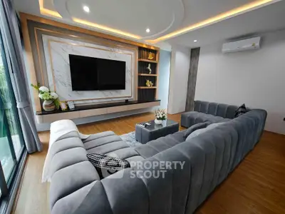 Luxurious modern living room with plush gray sectional sofa and large TV, perfect for relaxation.