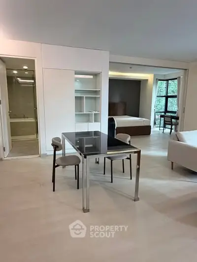Spacious modern apartment with open layout, featuring dining area and bedroom with large windows.