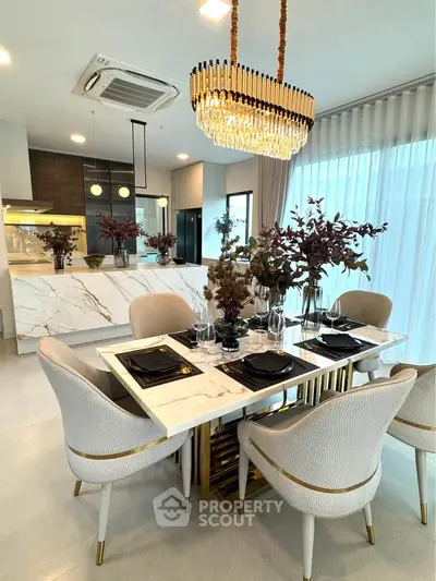 Luxurious dining area with elegant chandelier and modern kitchen in open layout