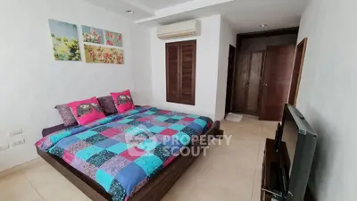 Cozy bedroom with colorful bedding and modern decor, featuring air conditioning and a flat-screen TV.