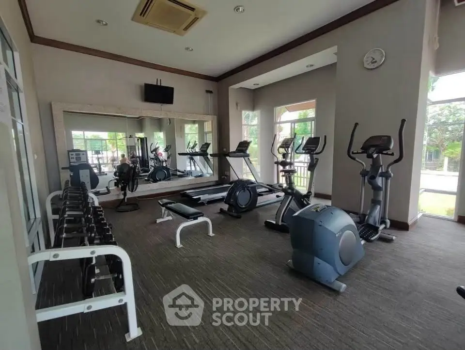 Spacious gym with modern equipment and large windows in luxury property.
