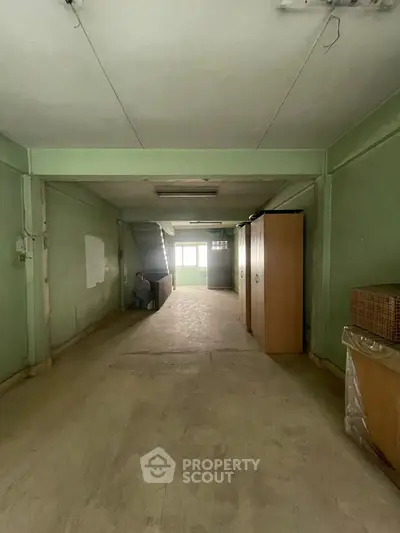 Spacious interior with potential for renovation, featuring green walls and ample natural light.