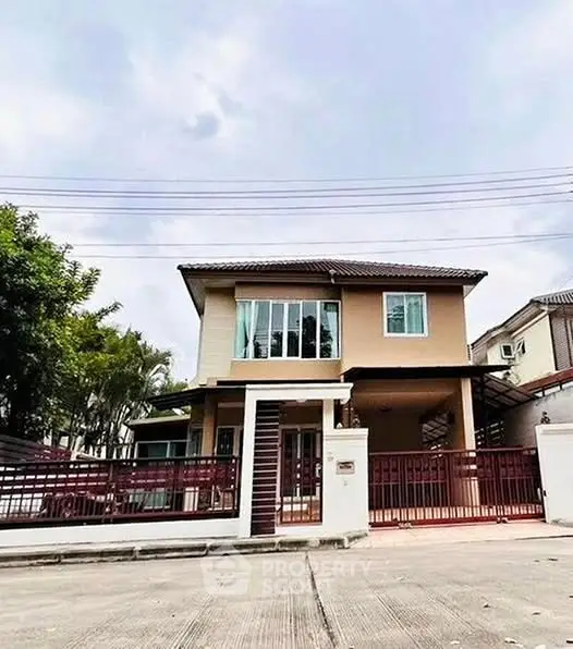 Charming two-story house with gated entrance and spacious driveway in suburban neighborhood.