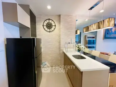 Modern kitchen with sleek design, featuring a black fridge, stylish lighting, and elegant decor.