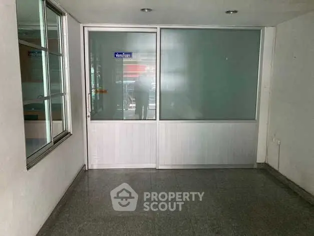 Spacious empty office space with glass partition and natural light.