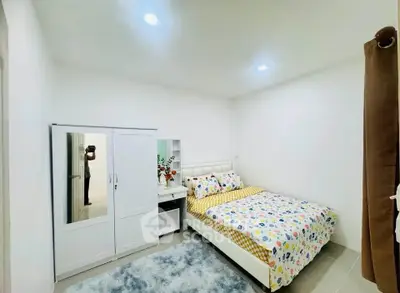 Cozy bedroom with modern decor, featuring a plush bed, wardrobe, and soft lighting for a serene ambiance.
