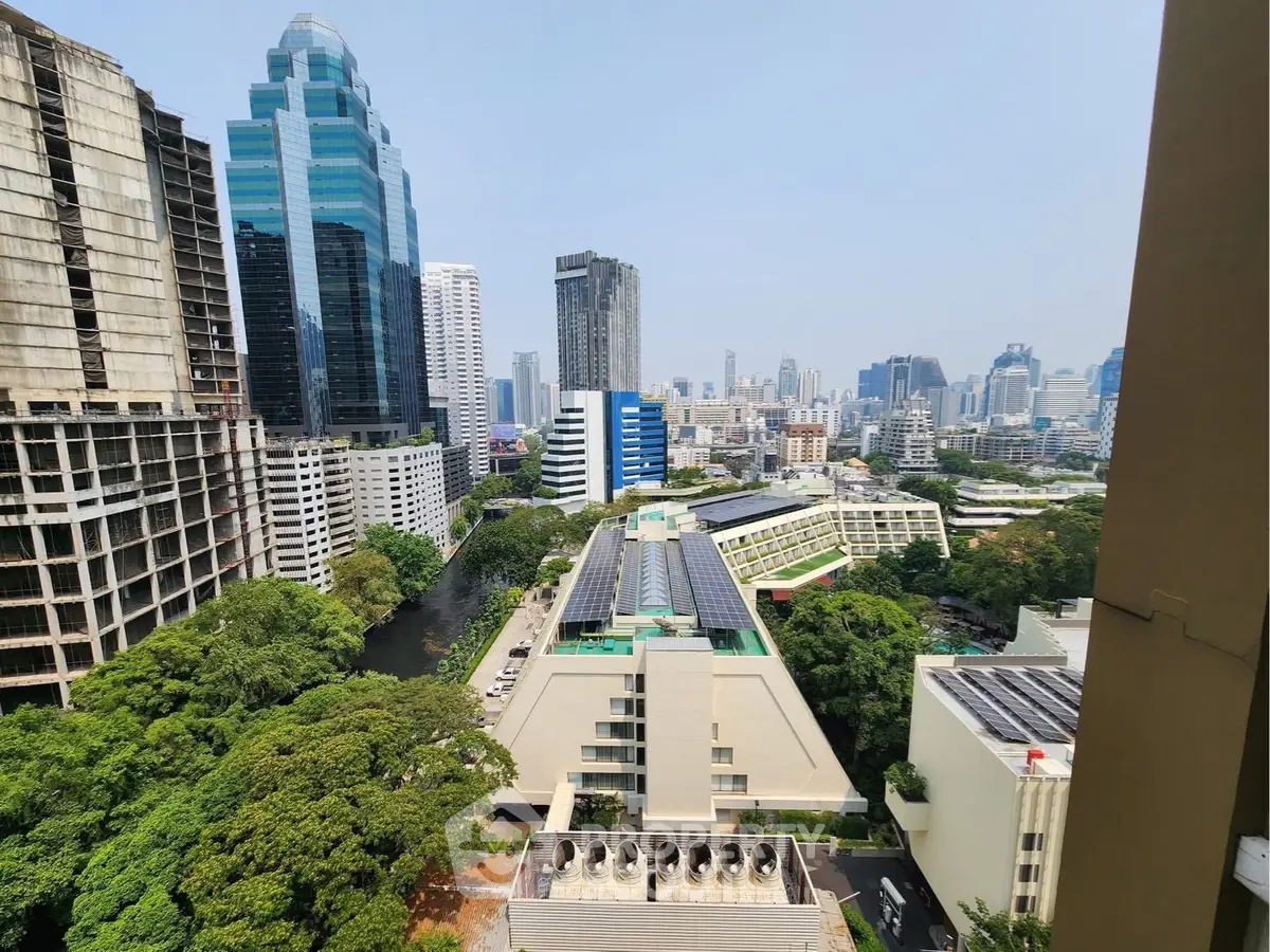 Stunning cityscape view from a high-rise building showcasing urban skyline and lush greenery.