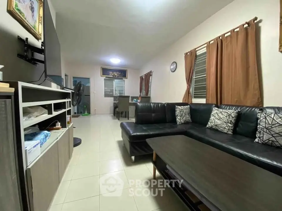 Spacious living room with modern black leather sofa and stylish decor