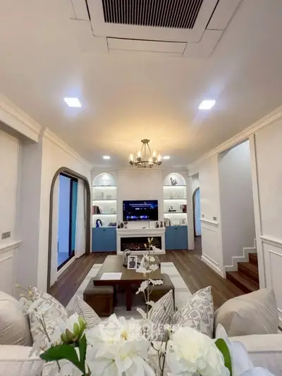 Elegant living room with built-in shelves and modern lighting, perfect for family gatherings.