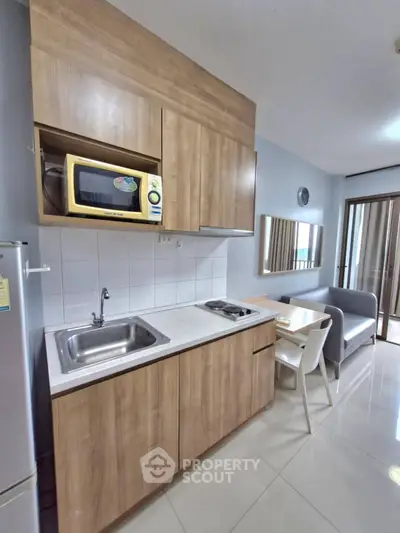 Modern kitchen with wooden cabinets, microwave, and cozy dining area in stylish apartment.