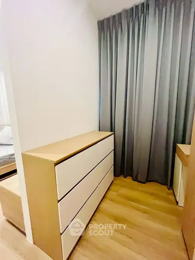 Modern bedroom with sleek dresser and floor-to-ceiling curtains, showcasing minimalist design.
