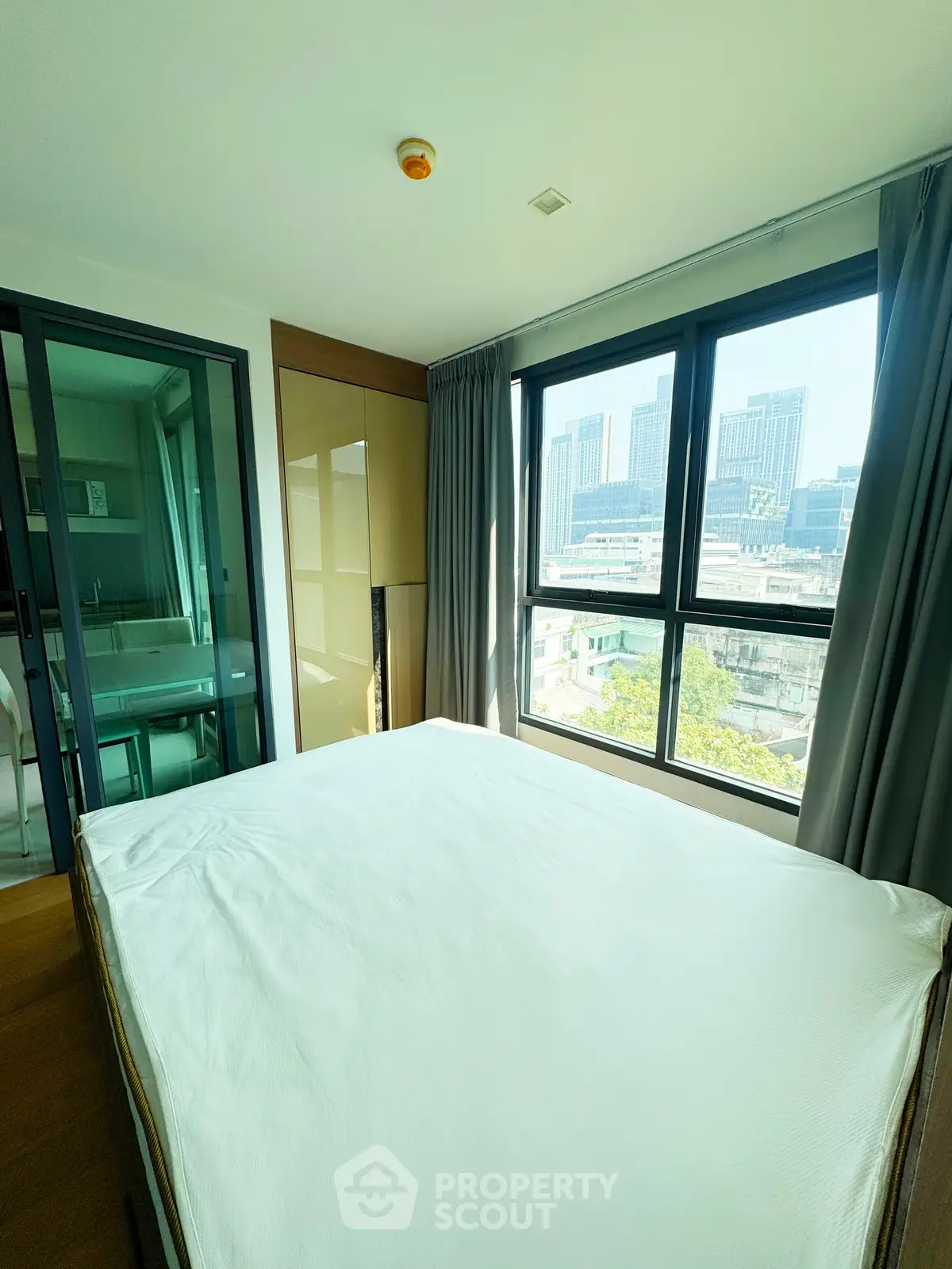 Modern bedroom with large windows and city view, featuring sleek design and natural light.
