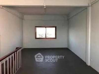 Spacious empty room with large window and staircase, ideal for customization.