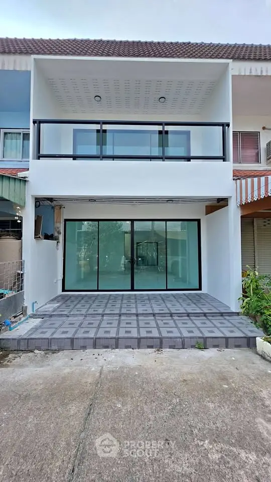 Modern townhouse exterior with spacious balcony and large glass doors.