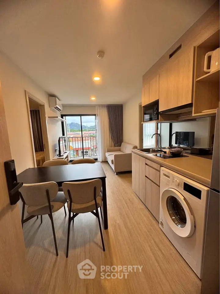 Modern open-plan living room and kitchen with balcony view in stylish apartment.