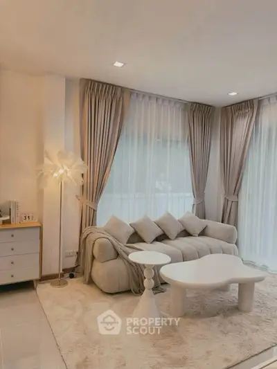 Elegant living room with plush sofa, modern decor, and floor-to-ceiling windows for natural light.