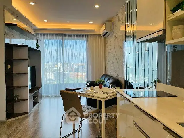 Modern living room with open kitchen and city view, featuring stylish decor and natural light.