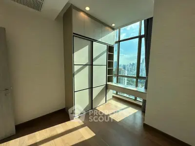 Modern bedroom with large windows offering stunning city views and ample natural light.