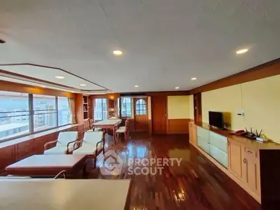 Spacious living room with wooden flooring and large windows offering city views.